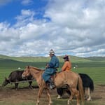 Mongolian nomad couple riding horses with ox cart on the steppe