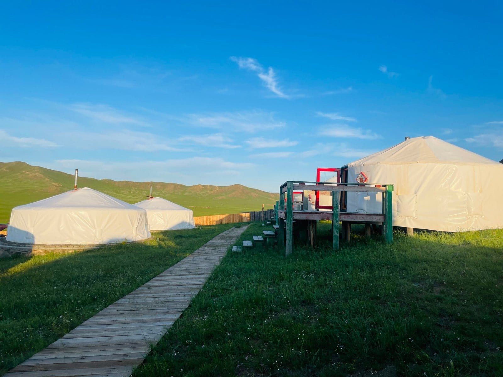 Traditional ger camp boardwalk deck overlooking green Mongolian steppe — Family Adventure Tour