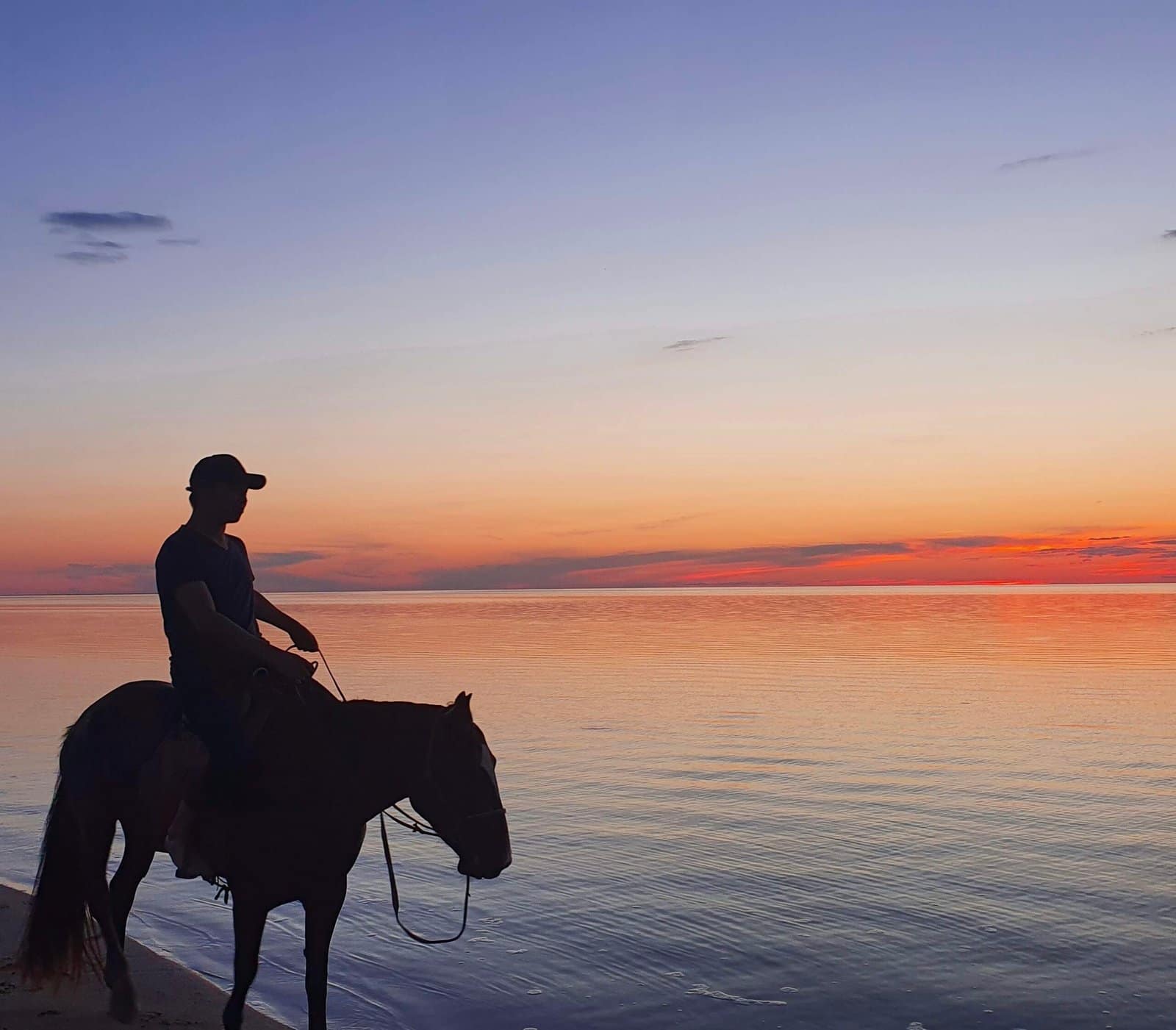 Mongolian rider silhouetted on horseback at lake sunset — Horseback Riding Steppe Trek Mongolia